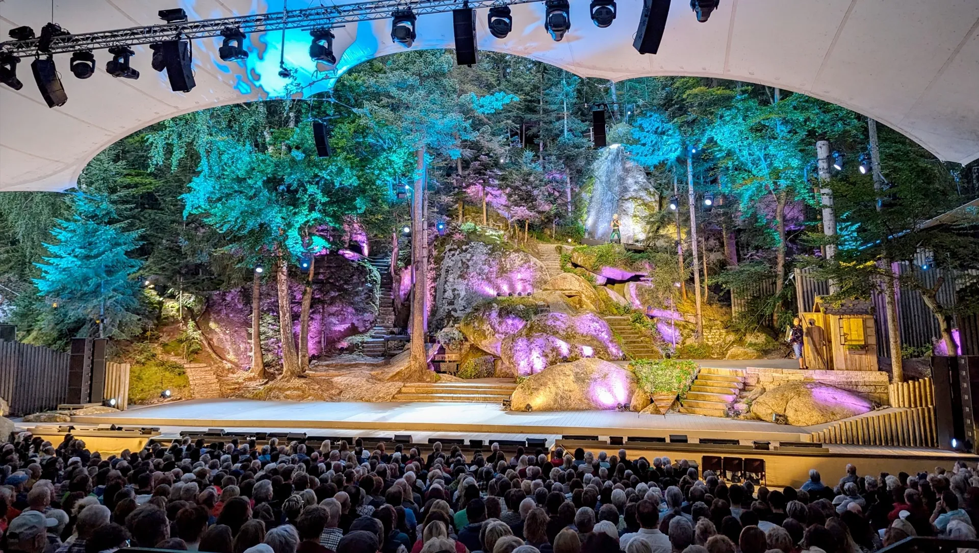 Blick von den Zuschauerplätzen auf eine bunte beleuchtete Naturbühne