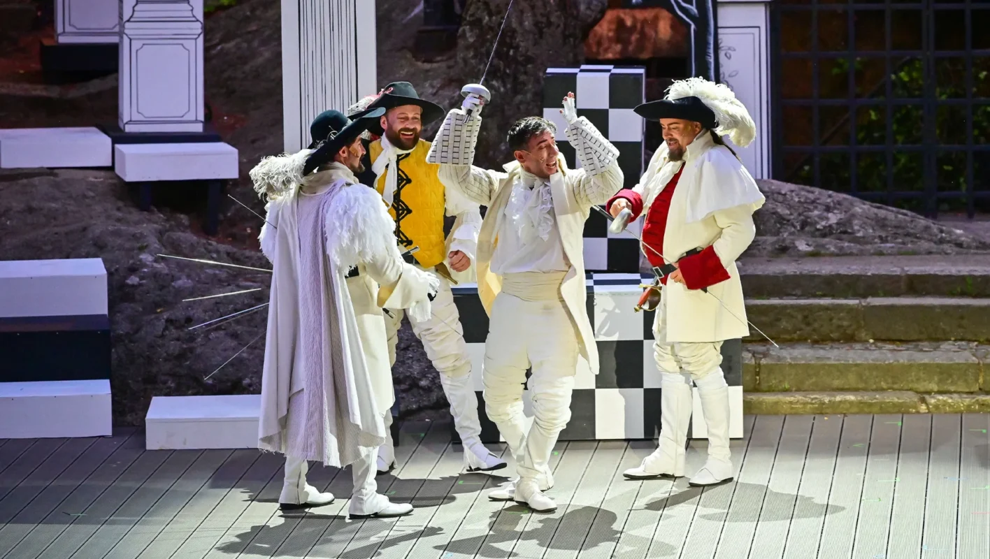 vier Musketiere in weißen Anzügen auf der Bühne