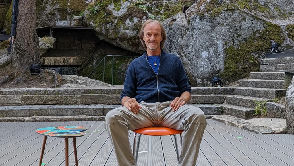 Eisi Gulp sitzend auf einer Bühne